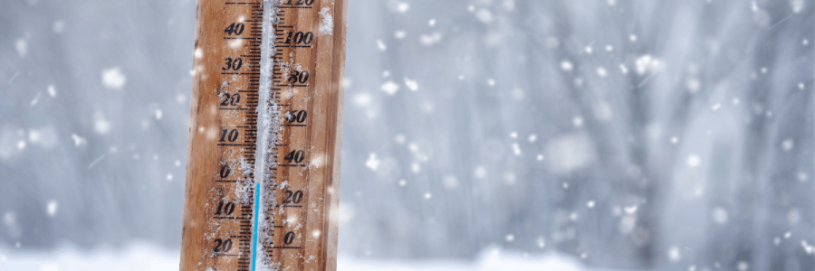 Snow with a thermometer sticking out showing freezing temperatures